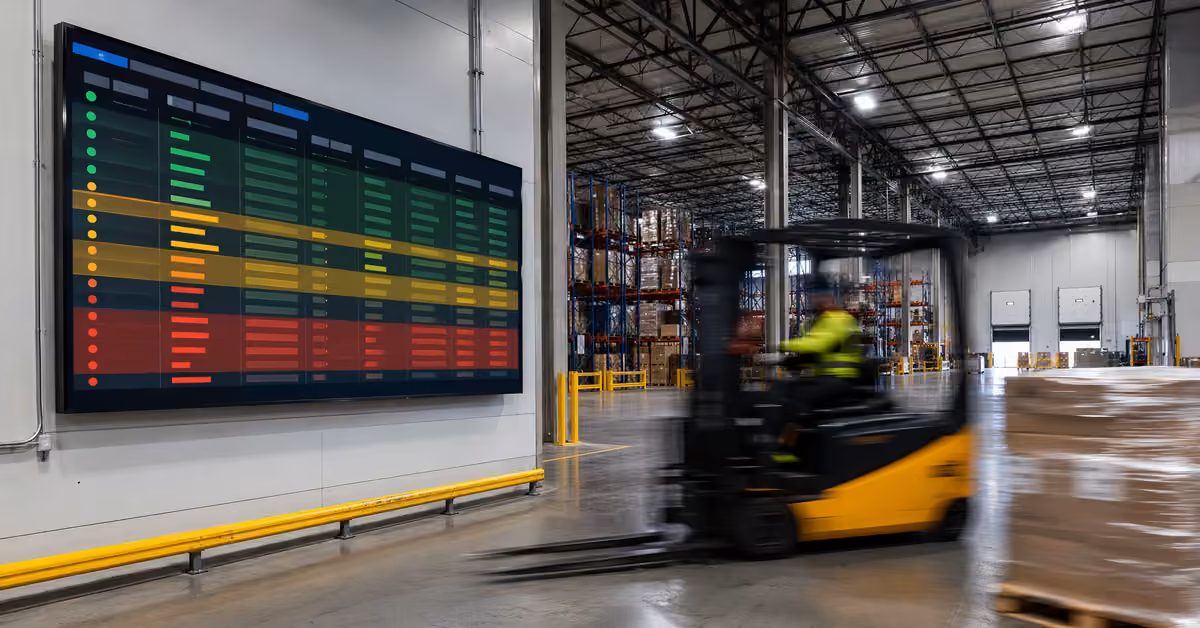 Forklift moving through a warehouse beneath a large live logistics dashboard.